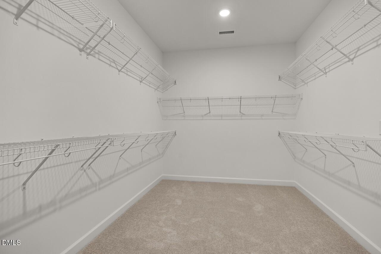 Walk-in closet with wire shelving and carpeted floor in Davidson Homes The Birch II C plan, Wake Forest, North Carolina