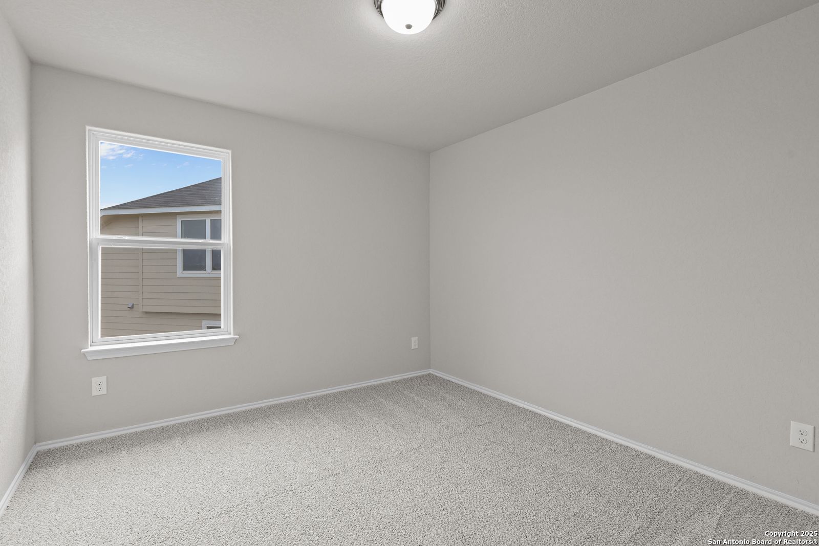 Bright secondary bedroom with neutral gray walls, carpet floor, and window view in Davidson Homes The Murray J, San Antonio