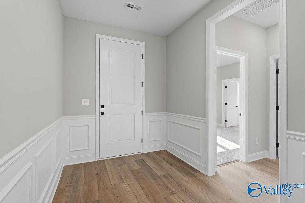 Elegant bedroom with wainscoted gray walls, white paneled doors, and hardwood floors in Davidson Homes The Montgomery B, Hartselle, AL