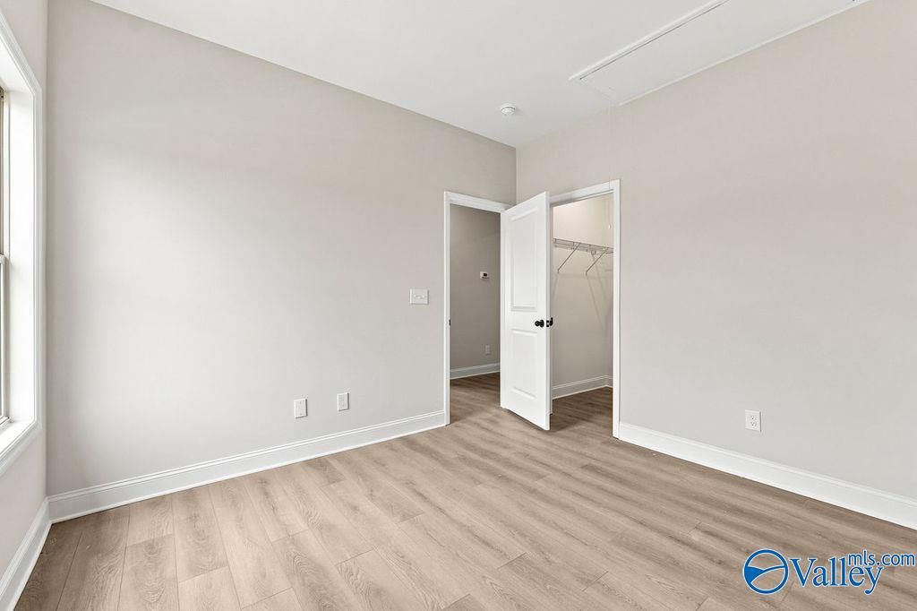 Bright bedroom with neutral walls, wood-look flooring, and walk-in closet in The Camilla B at The Retreat at Cain Park.