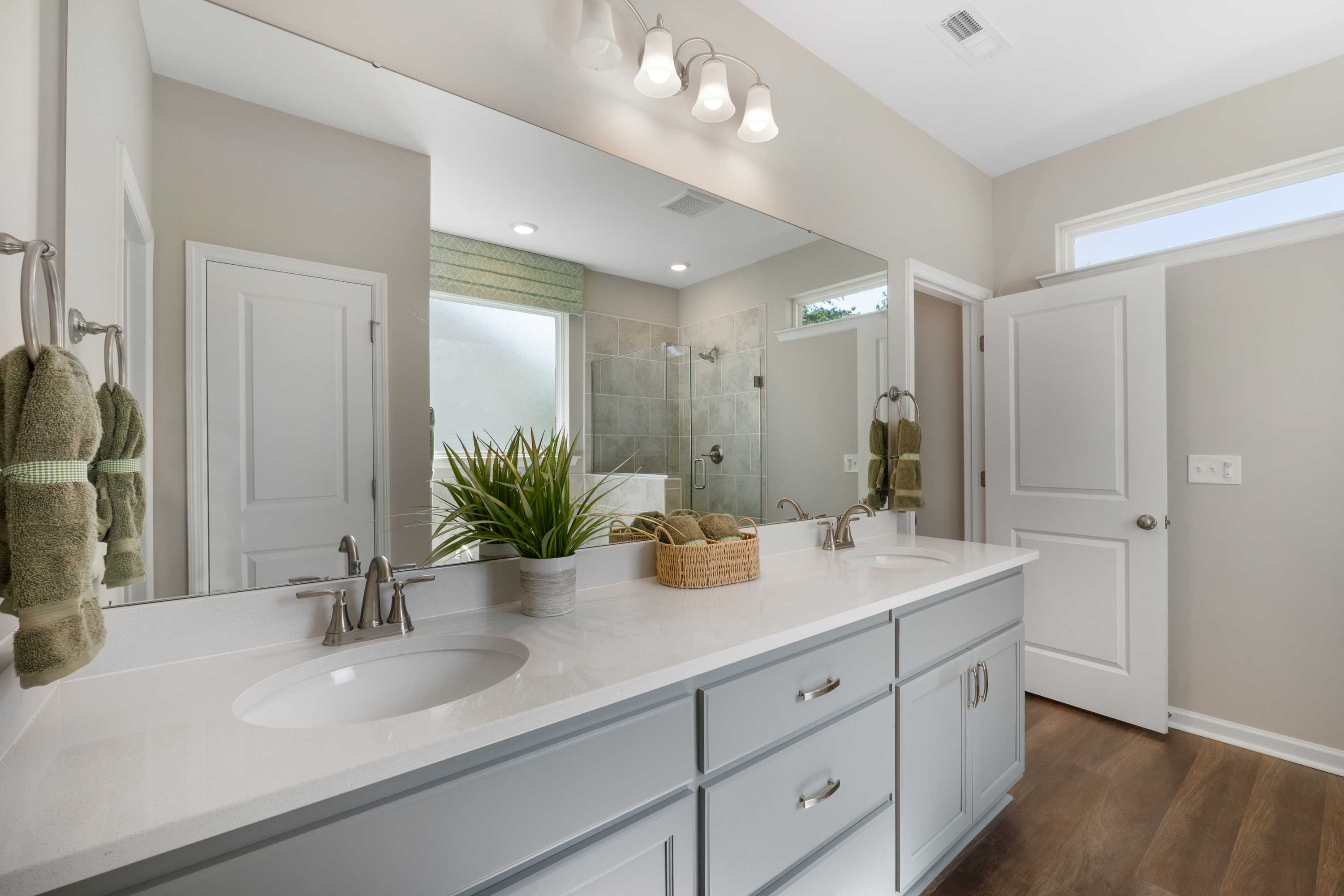 Spacious modern bathroom at Evergreen Mill in Madison, Alabama with double gray vanity, large mirror, walk-in shower, and hardwood floors