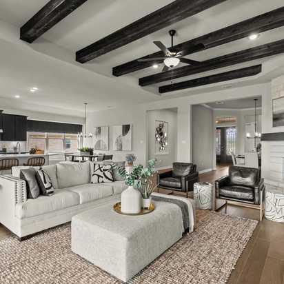 Spacious open-concept living room at Potranco Oaks in Castroville Texas with exposed wood beams, white sofa, and stone fireplace