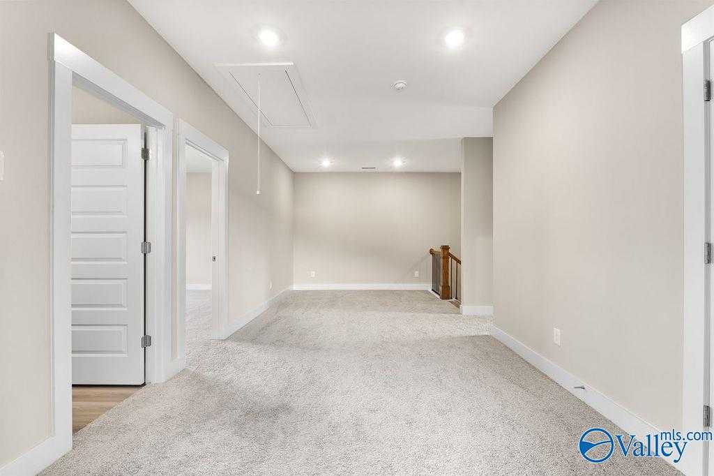 Spacious upstairs hallway with beige walls, recessed lights, and carpeted floor in Evermore Homes The Oxford, Owens Cross Roads, AL