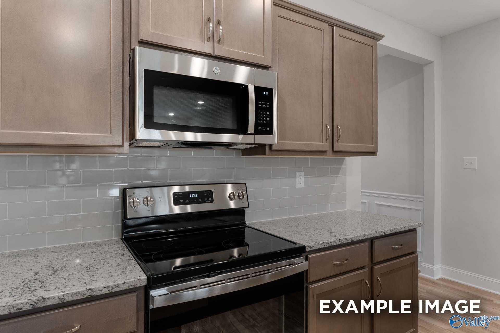 Modern kitchen featuring stainless steel range and microwave, granite countertops, subway tile backsplash in Davidson Homes Cumberland B, Decatur, AL