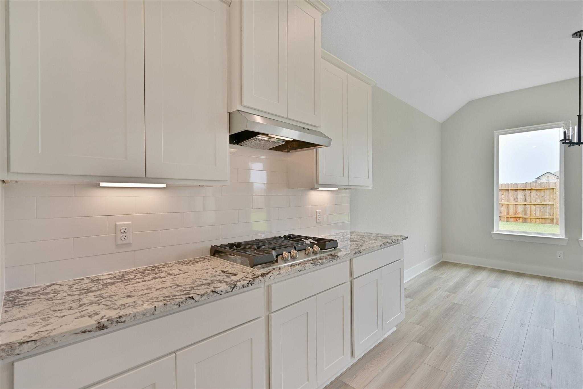 Modern white kitchen with granite counters, subway tile backsplash, gas range in Davidson Homes Edward C, Lago Mar Texas City