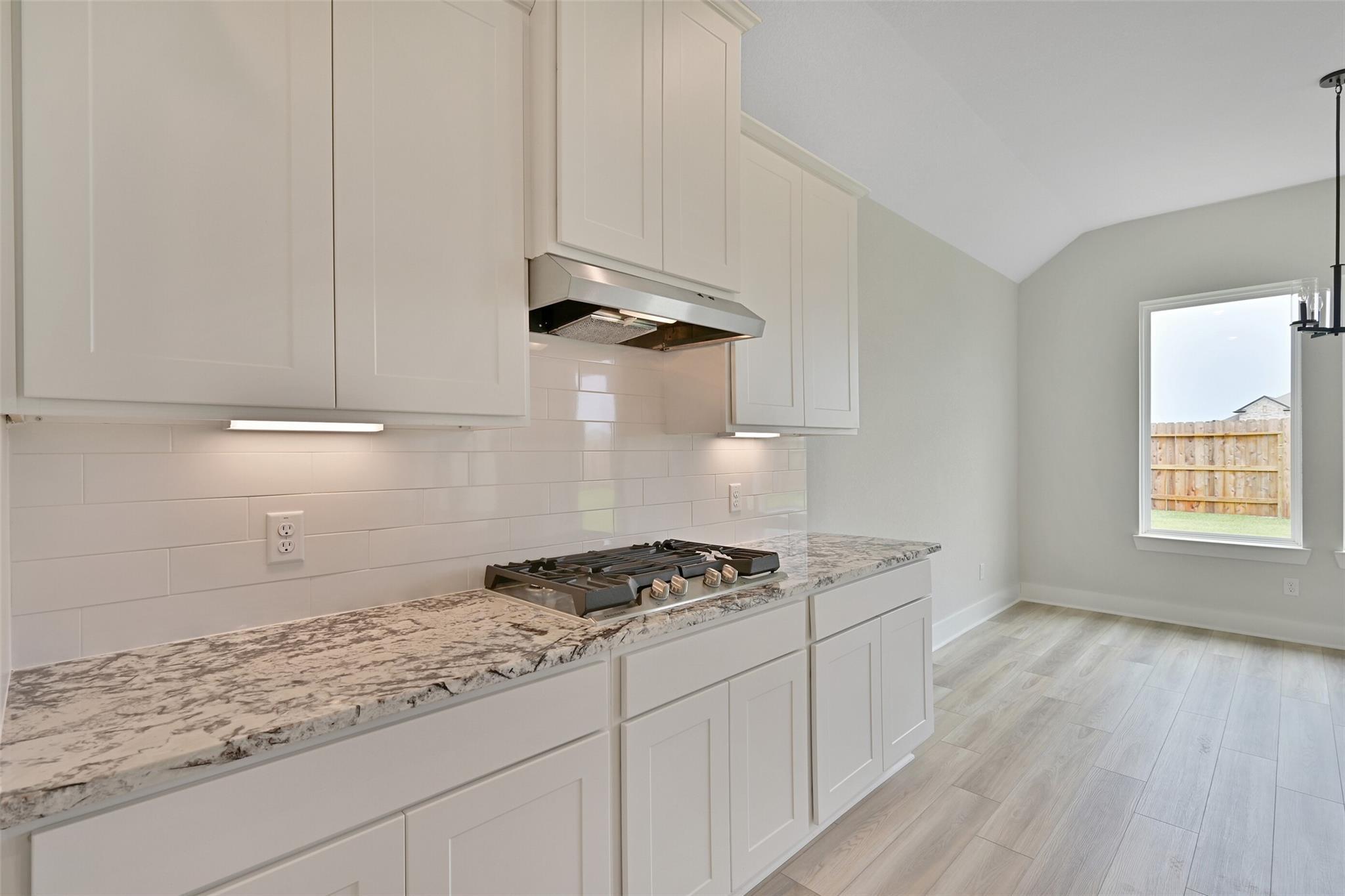 Modern white kitchen with granite counters, subway tile backsplash, gas range in Davidson Homes Edward C, Lago Mar Texas City