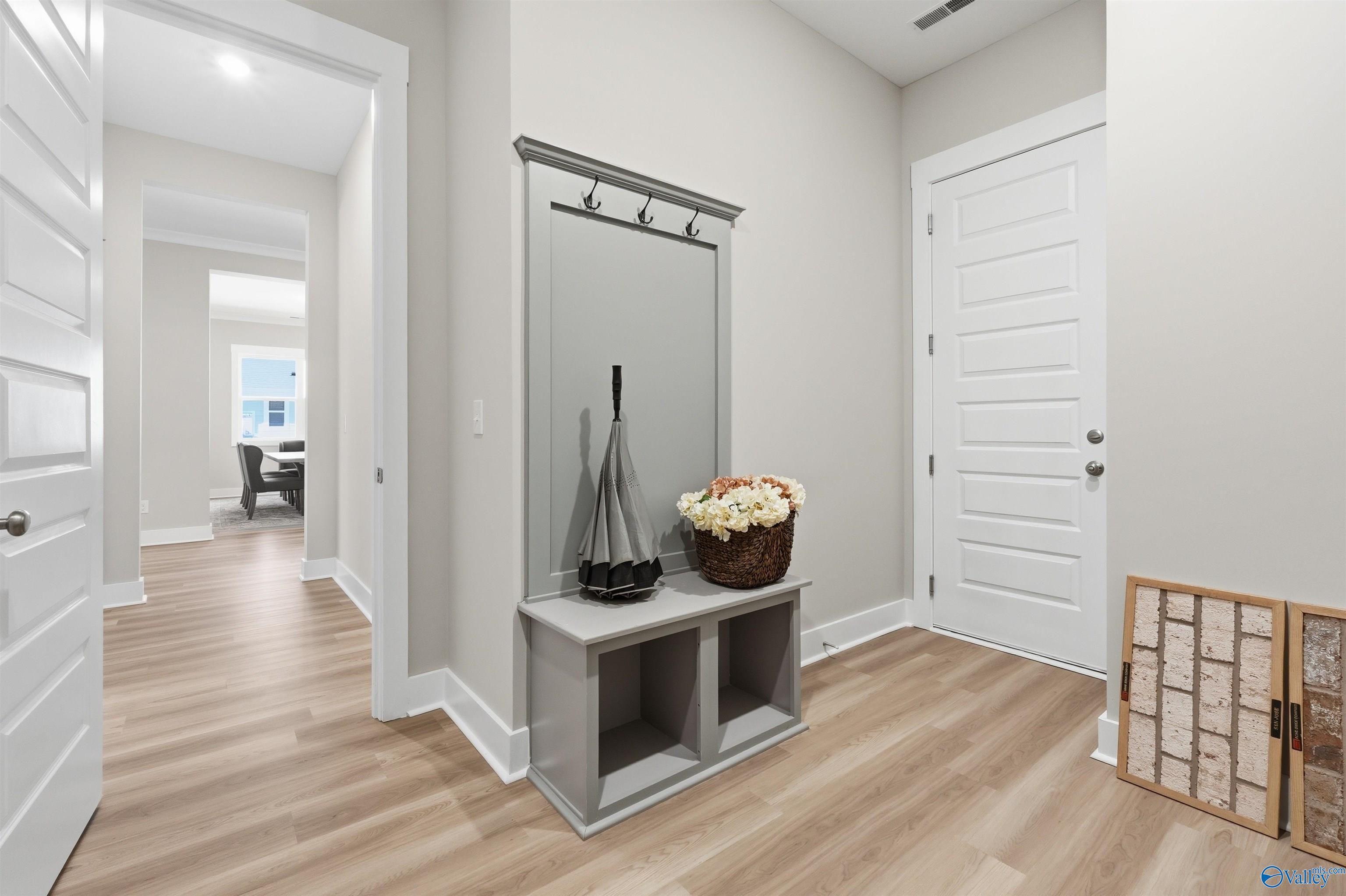 Elegant gray entryway bench with mirror, hooks, umbrella, and flower basket on oak floors in Evermore Homes The Oxford B, Owens Cross Roads