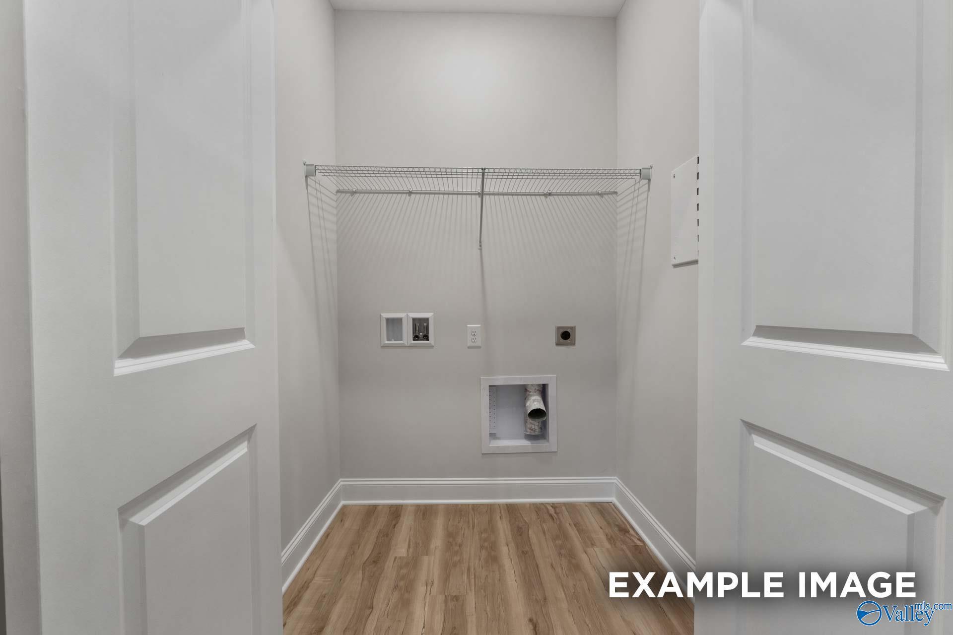 Spacious laundry room with wire shelving, washer/dryer hookups, and hardwood floors in Davidson Homes The Cumberland B, Decatur AL