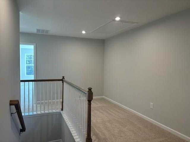 Spacious upstairs hallway with white balustrade railing, gray walls, and beige carpet in Davidson Homes Marion A, Winder, GA