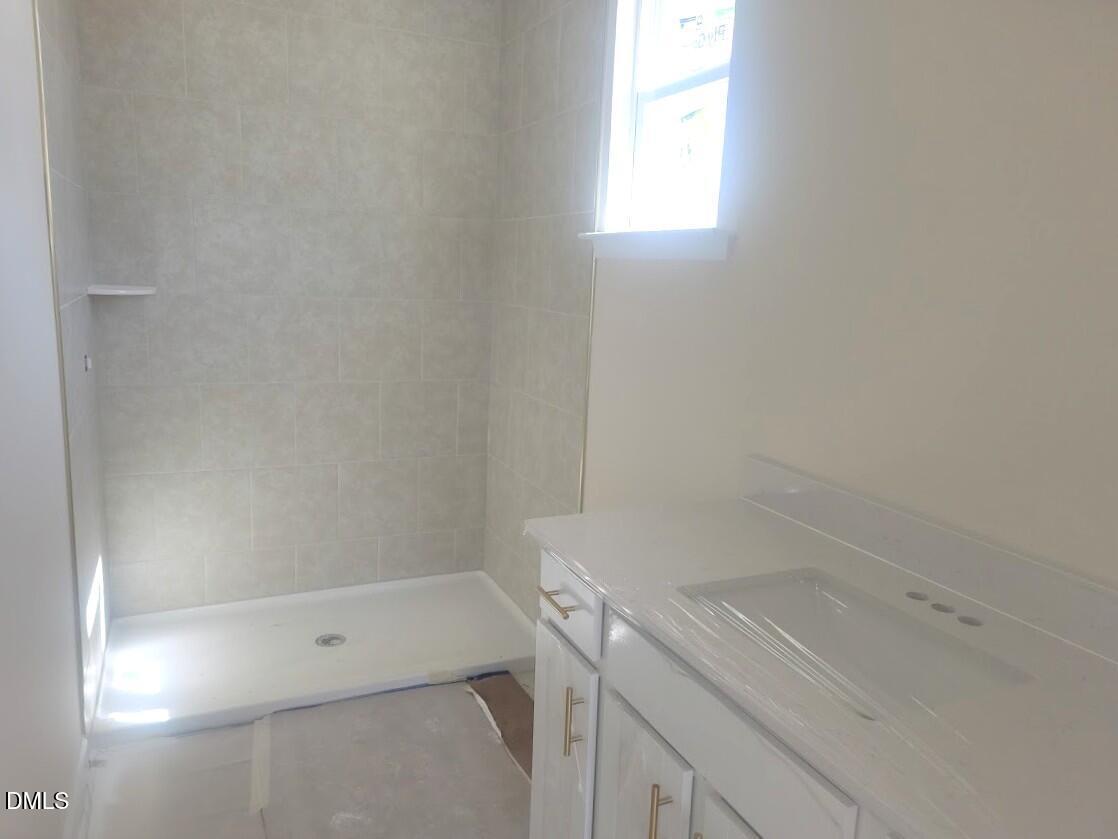 Contemporary bathroom with tiled walk-in shower and white vanity in Davidson Homes The Cypress B II, Angier, North Carolina