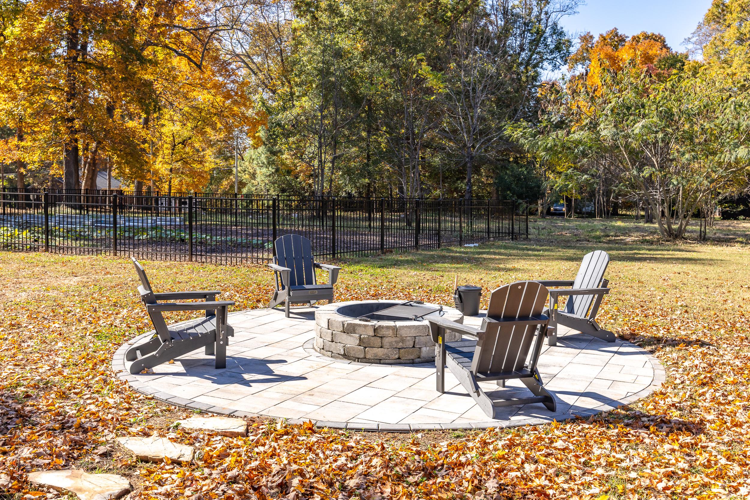 Cozy fire pit with Adirondack chairs on circular paver patio amid autumn trees at Stagecoach Corner in Mebane, North Carolina