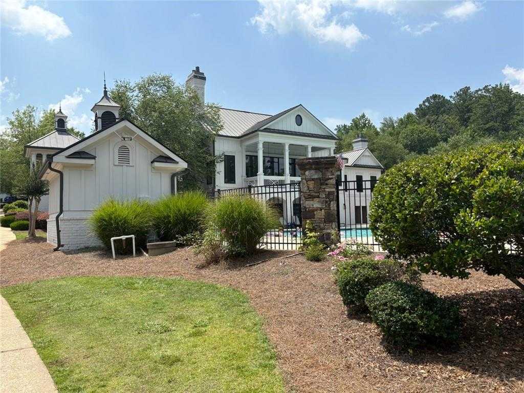 Elegant two-story white home with pool, black iron fence, and detached garage amid lush landscaping in Riverwood, Dallas, Georgia