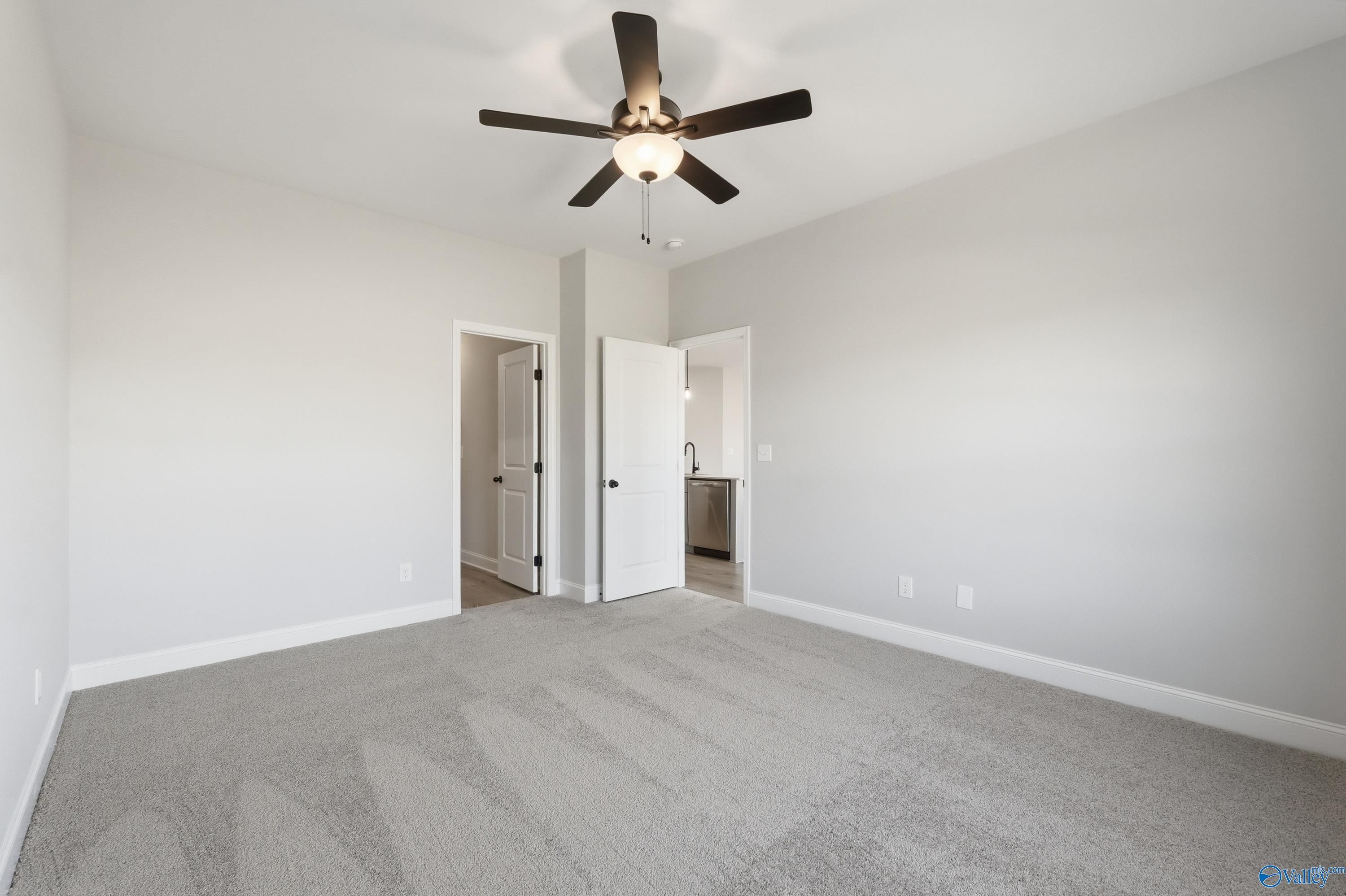 Spacious bedroom with gray carpet, ceiling fan, and en-suite bathroom sink in Davidson Homes The Franklin C, New Market, Alabama