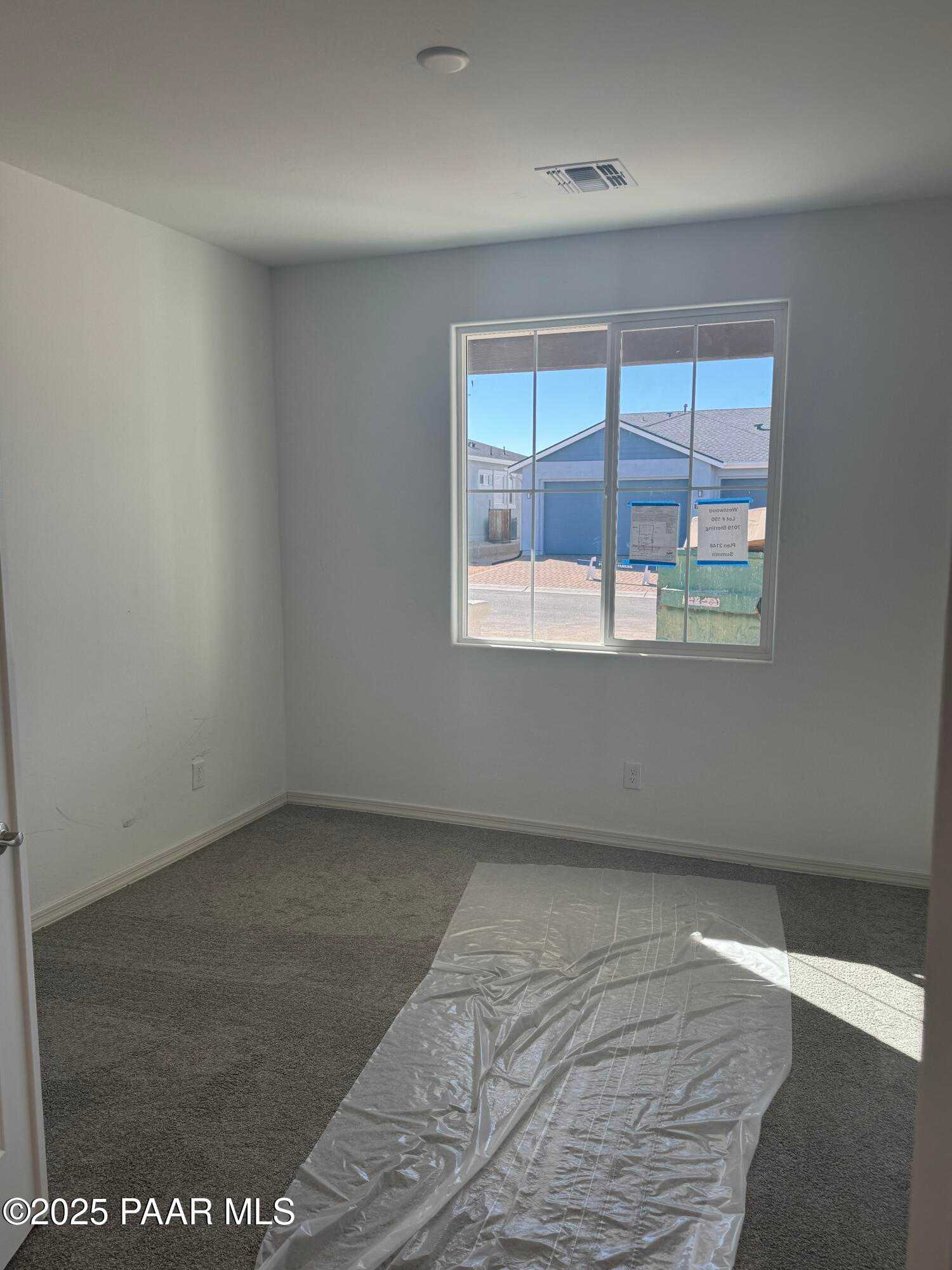 Bright empty bedroom with large sunny window and protective floor covering in Davidson Homes The Summit A, Prescott, Arizona