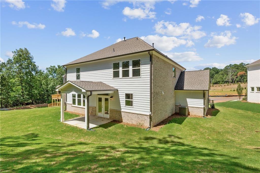 Two-story Hickory E home with 3-car garage, covered porch, and lush yard in Melody Lakeside Estates, Buford, Georgia