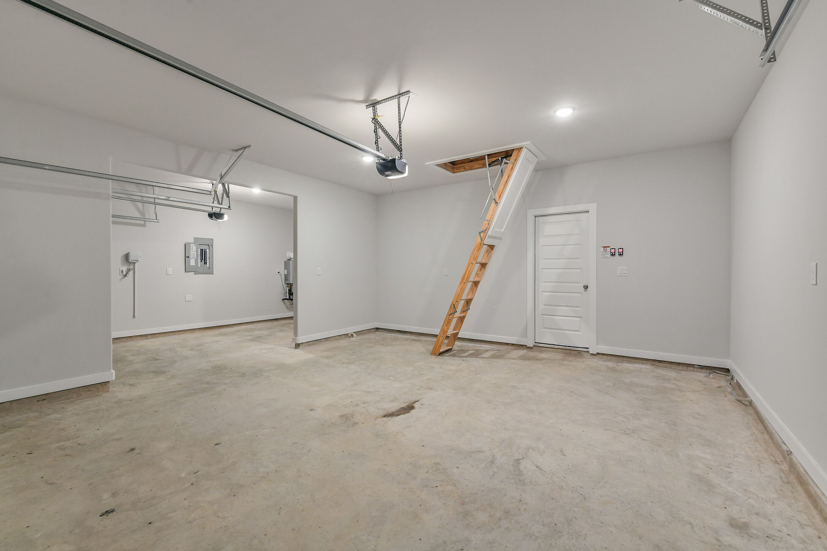 Spacious 3-car garage with pull-down attic stairs and concrete floor in Davidson Homes The Colorado G, Magnolia, Texas