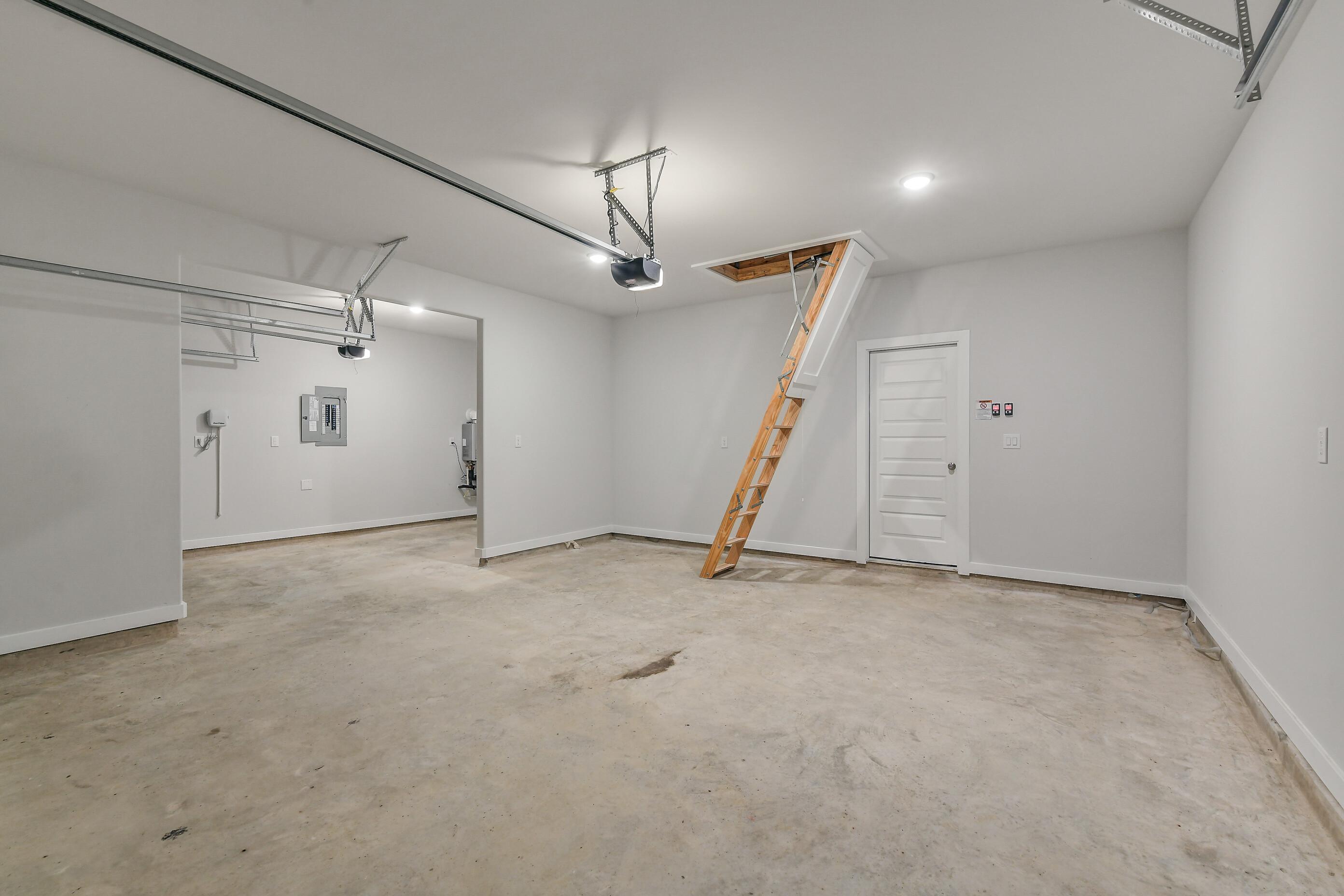 Spacious 3-car garage with pull-down attic stairs and concrete floor in Davidson Homes The Colorado G, Magnolia, Texas