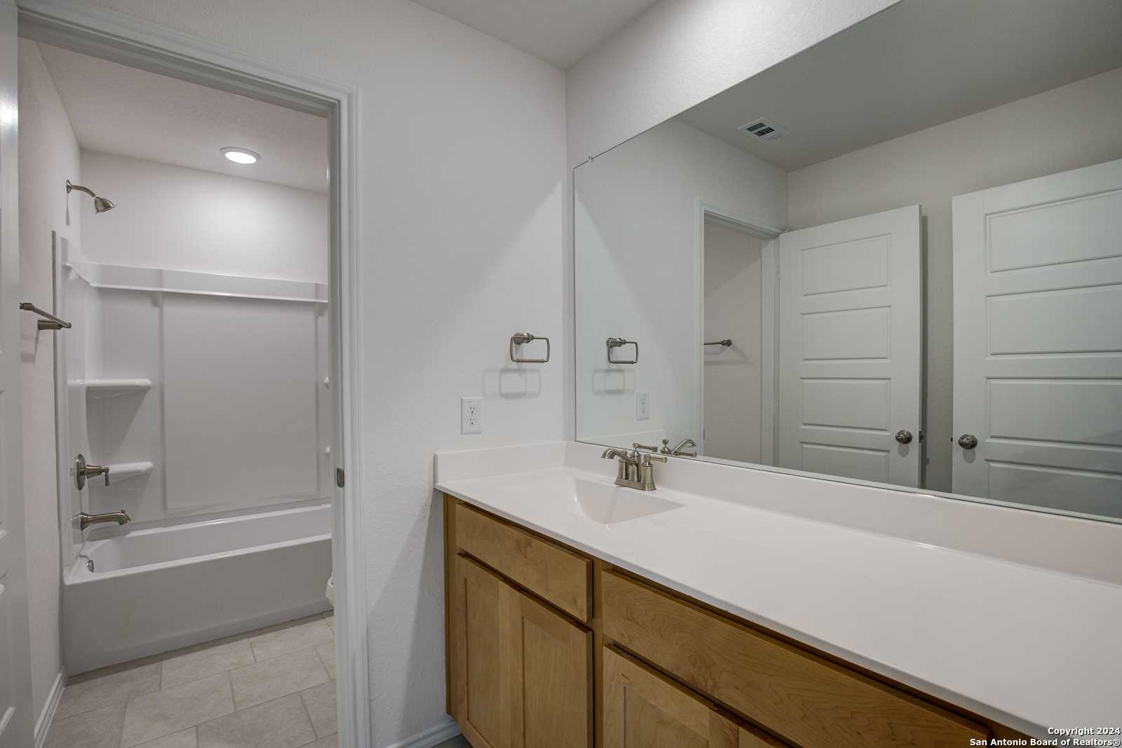 Bright secondary bathroom with double oak vanity, soaking tub, glass shower in Davidson Homes The Douglas D, Seguin, Texas