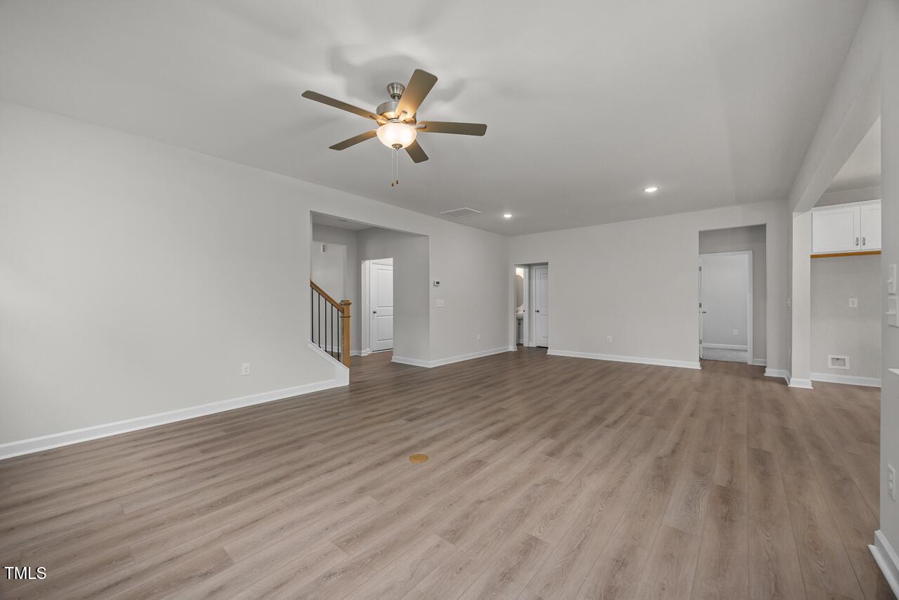 Spacious open living area with hardwood floors, ceiling fan, and white kitchen cabinets in Davidson Homes The Aspen B, Wake Forest NC