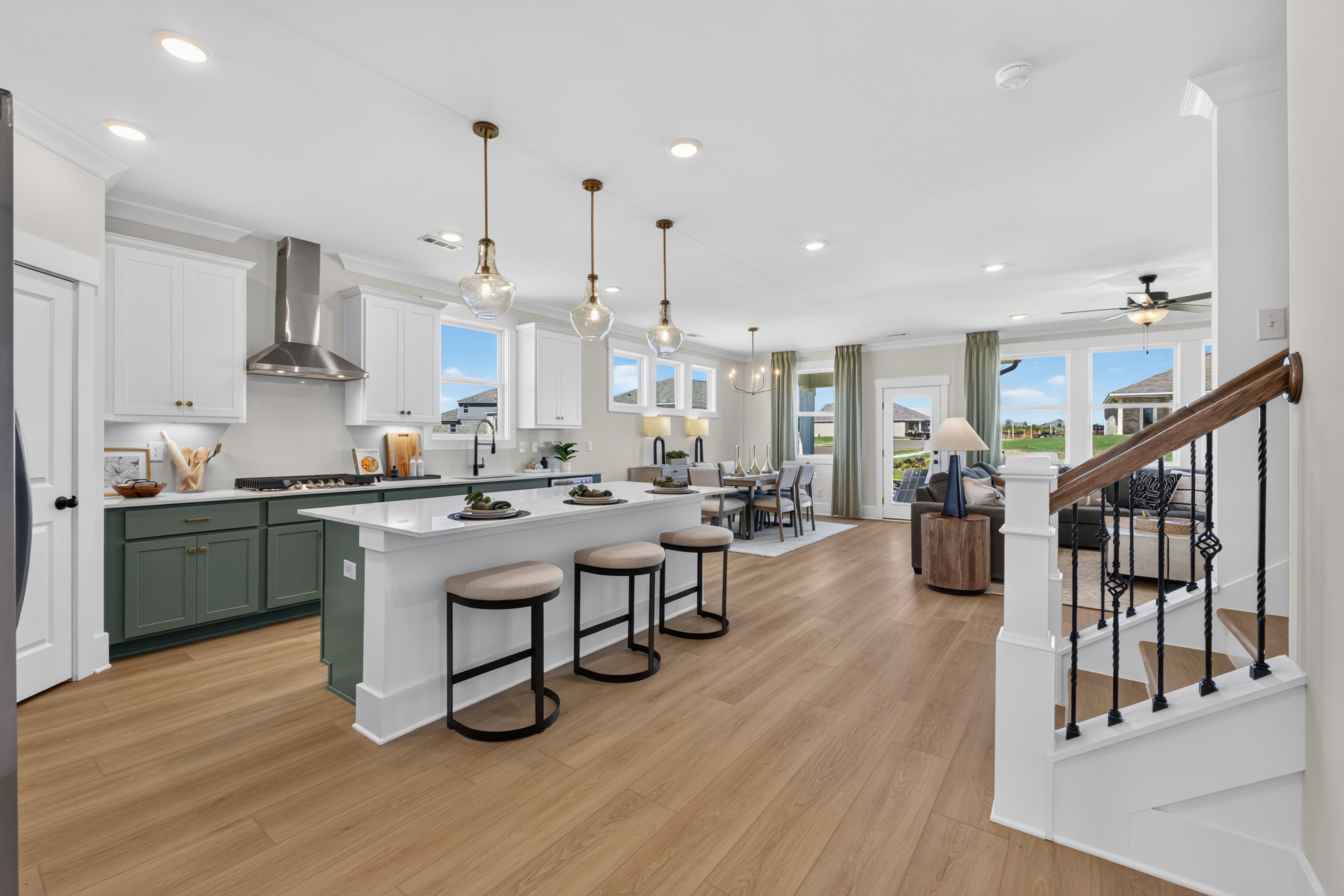 Open-concept kitchen with green cabinetry, white island, and hardwood floors at Evergreen Mill by Davidson Homes in Madison, AL