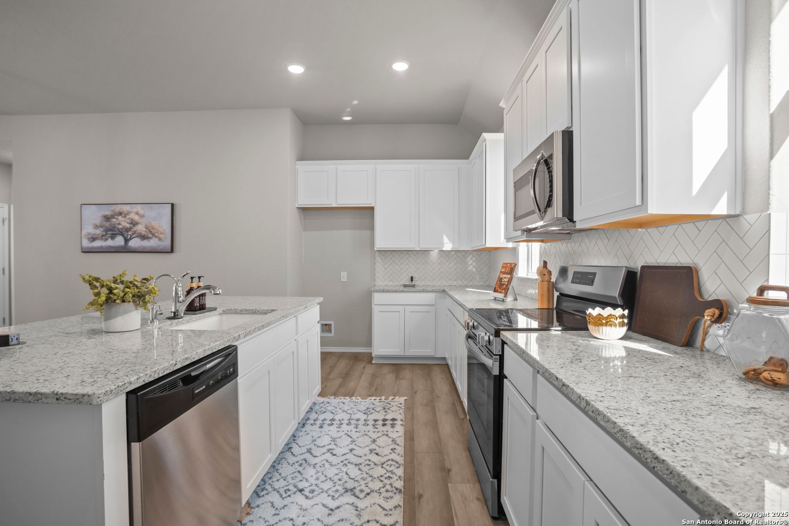 Modern white kitchen with granite island, stainless appliances, subway tile backsplash in The Collin B by Davidson Homes, Seguin TX