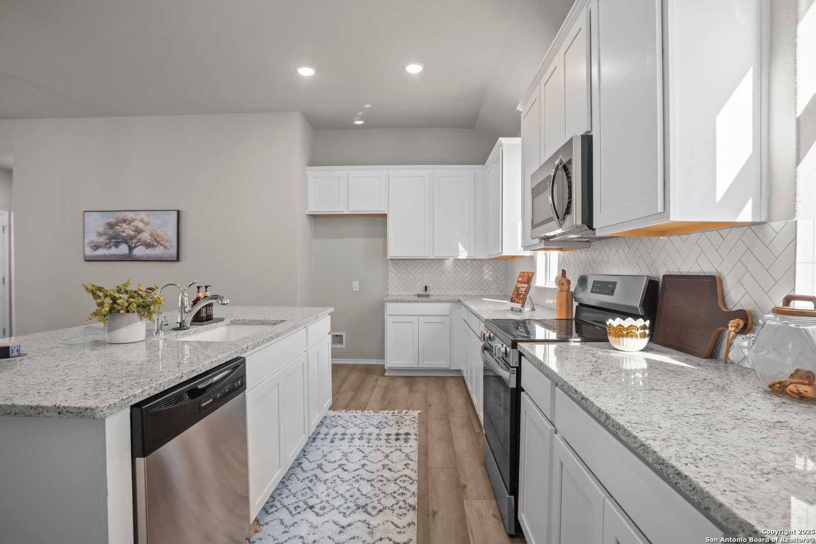 Modern white kitchen with granite island, stainless appliances, subway tile backsplash in The Collin B by Davidson Homes, Seguin TX