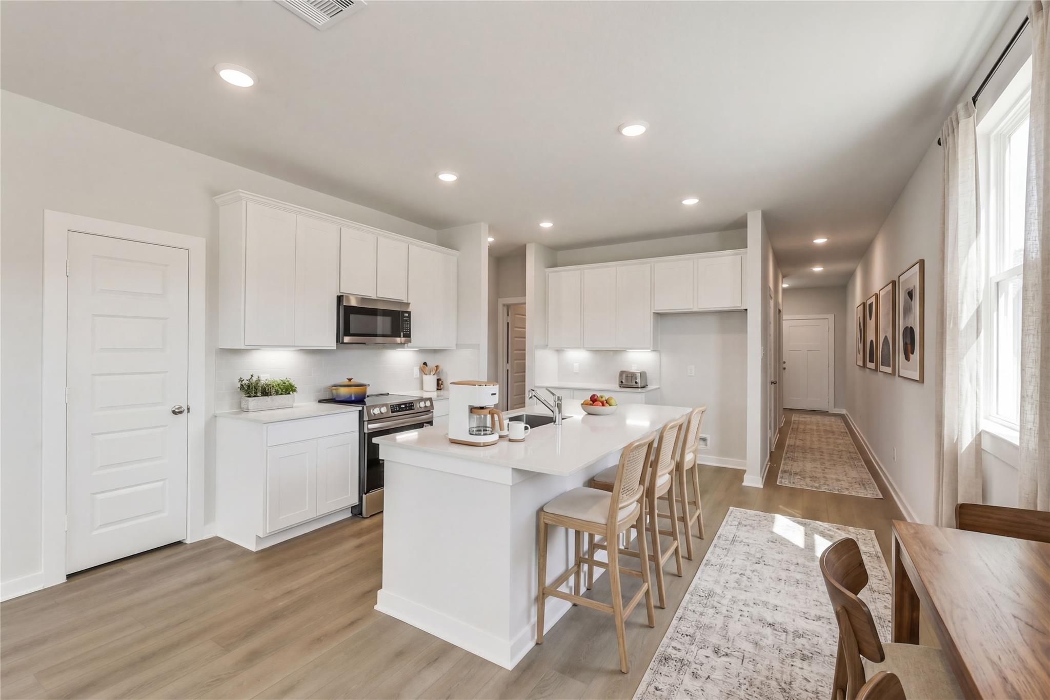 Modern open-concept kitchen with white cabinets, quartz island, stainless appliances in Davidson Homes The Frio G, Conroe, Texas