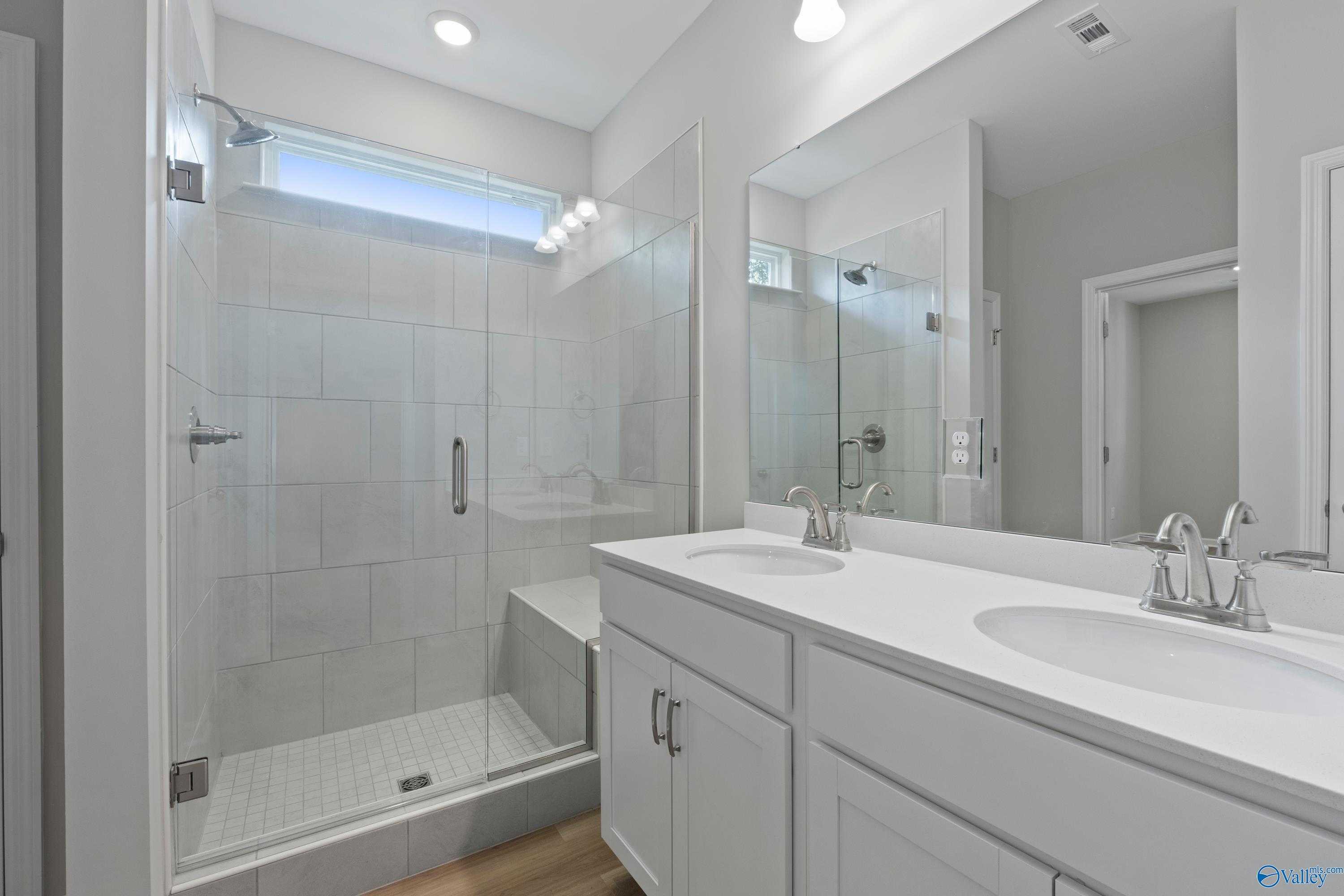 Elegant master bathroom with frameless glass shower, double white vanity, and subway tile in Davidson Homes The Polaris, Fayetteville, TN