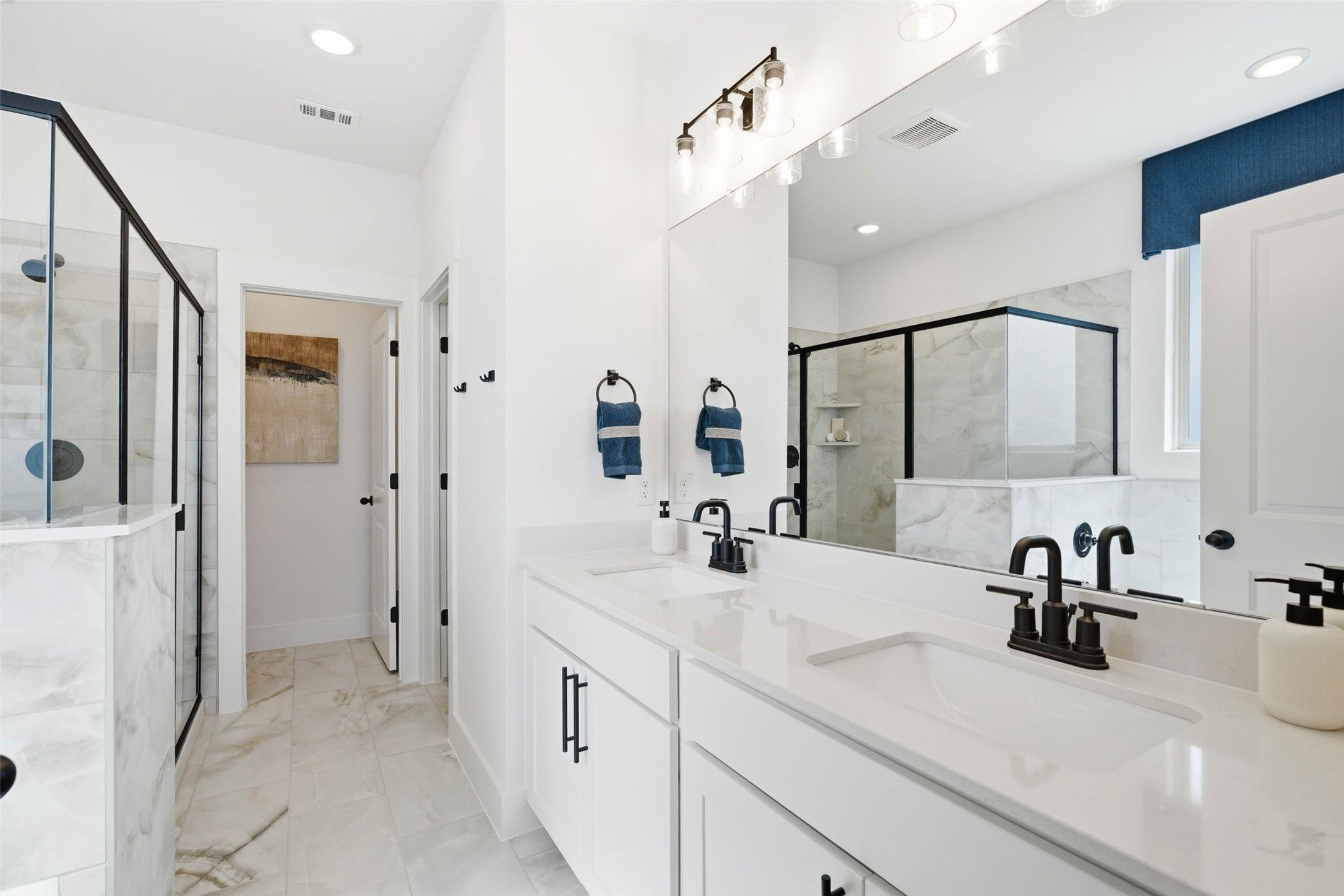Modern master bathroom with dual vanities, matte black fixtures, marble-look tile, and glass shower in Davidson Homes The Laurel N, Royse City
