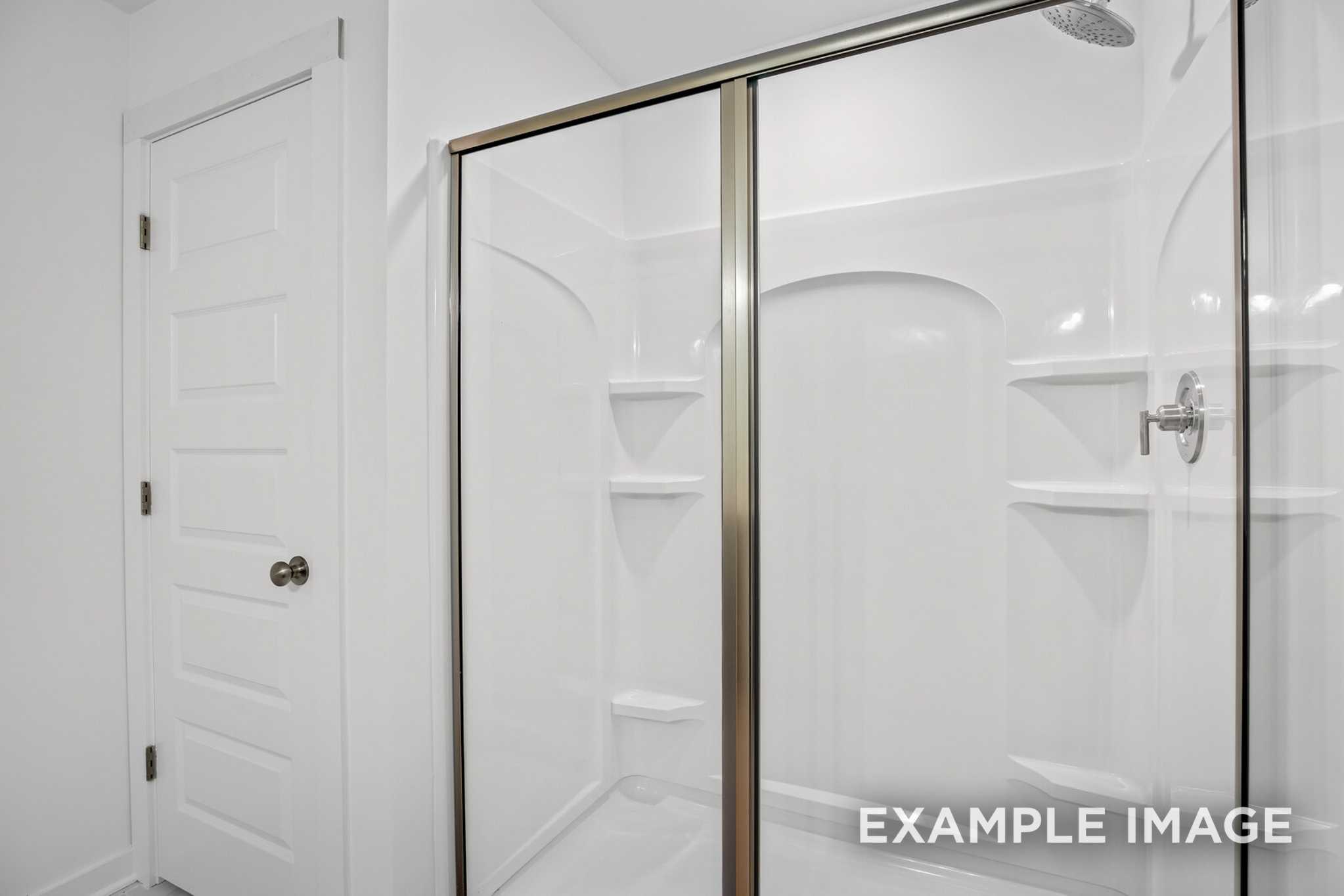 Modern master bath shower in The Murray B with arched glass enclosure and built-in shelves