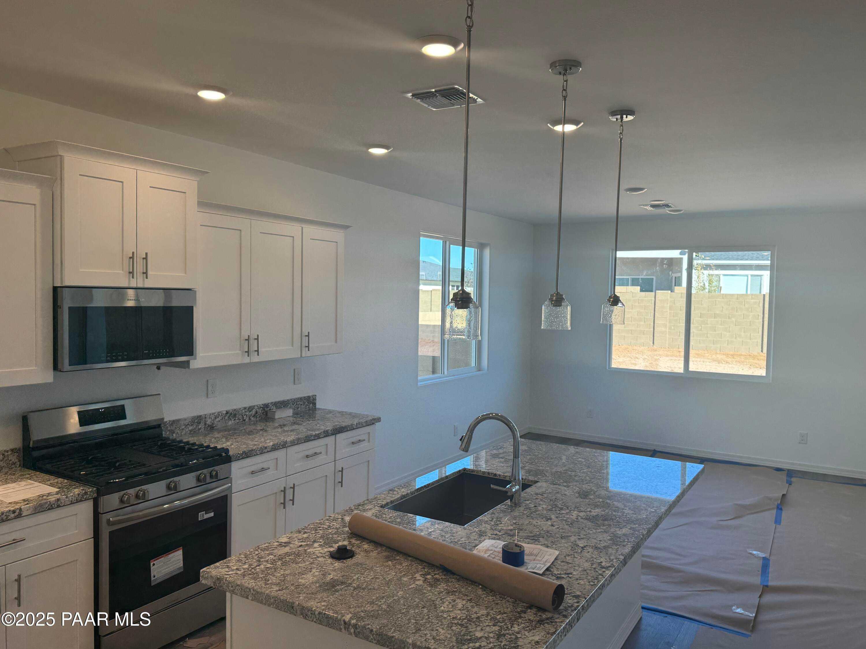 Modern kitchen with granite island, stainless appliances, white cabinets, pendant lights in Davidson Homes The Summit A, Prescott, AZ