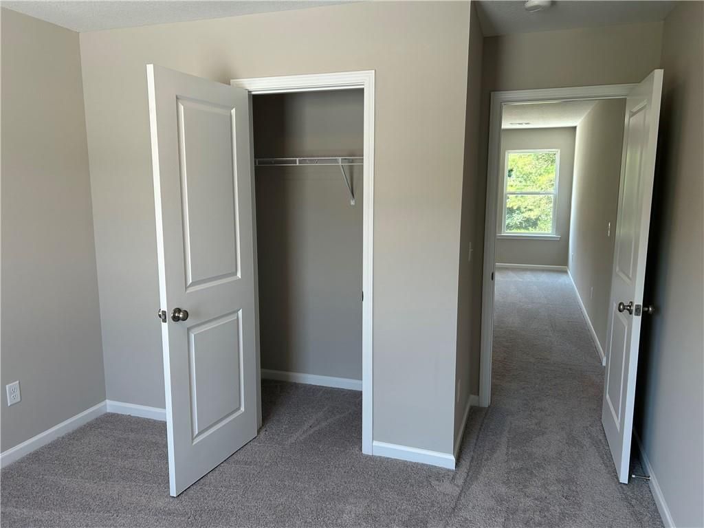 Spacious secondary bedroom with walk-in closet, beige walls, and hallway view in Davidson Homes The Washington, Phenix City, Alabama