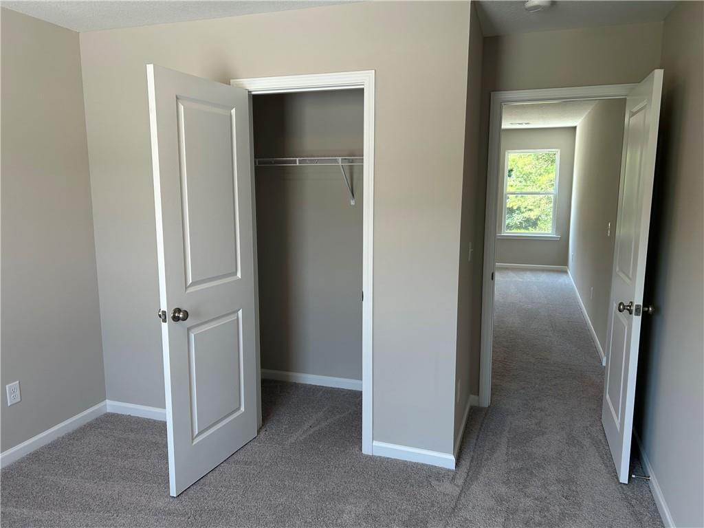 Spacious secondary bedroom with walk-in closet, beige walls, and hallway view in Davidson Homes The Washington, Phenix City, Alabama