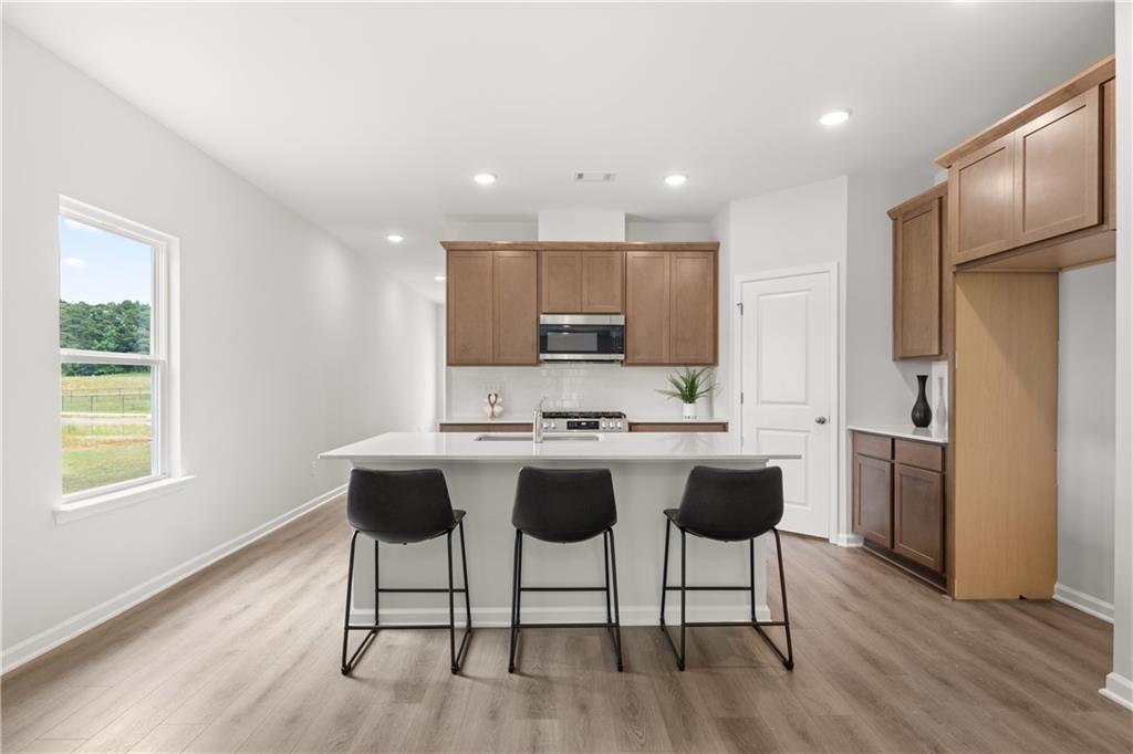Modern kitchen with island, wood cabinets, and bar seating in The Sinclair B floor plan at Cedar Farms in Winder, Georgia.