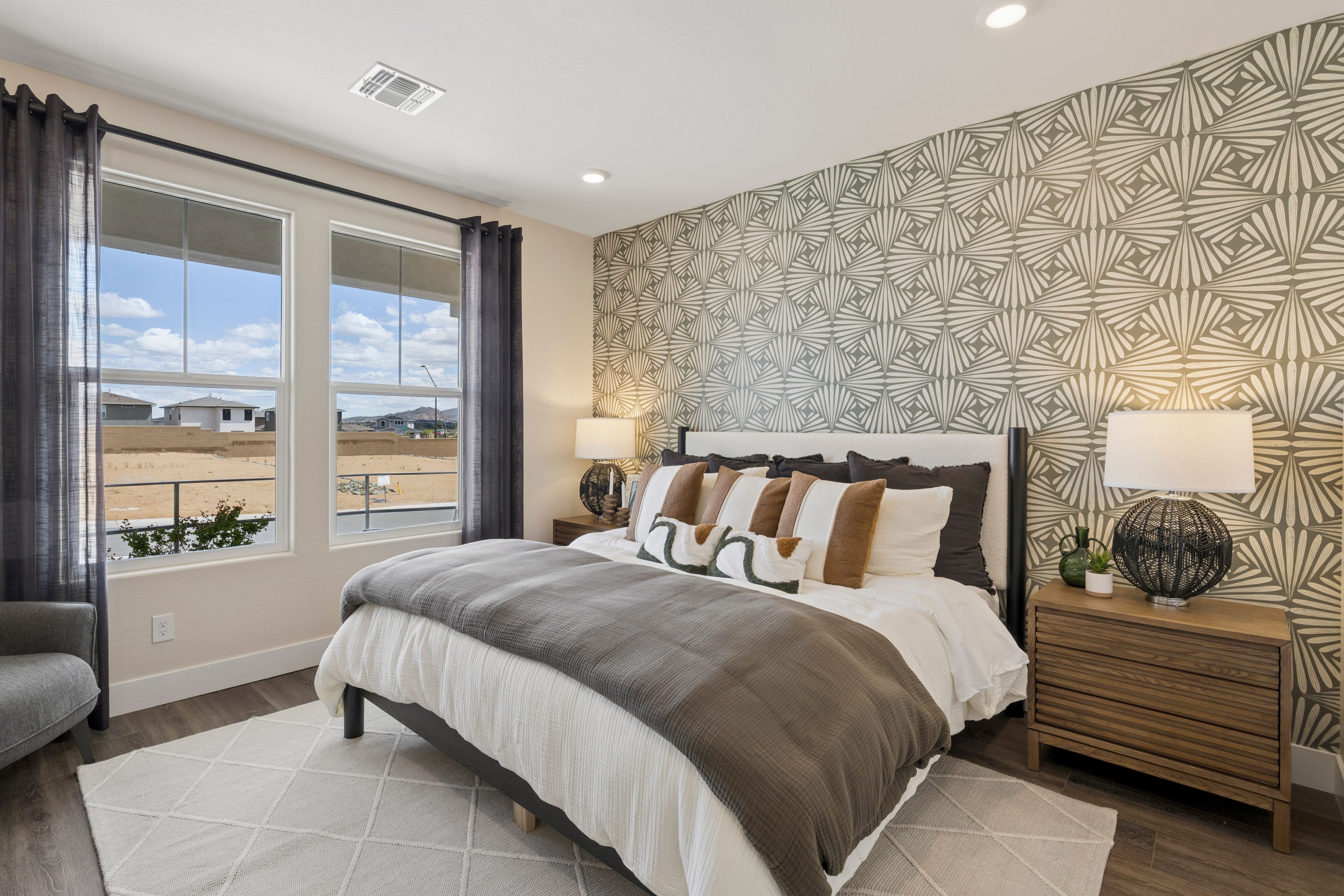 Spacious master bedroom in South Ranch Western Collection Prescott AZ with geometric wallpaper, king bed, desert views, and hardwood floors