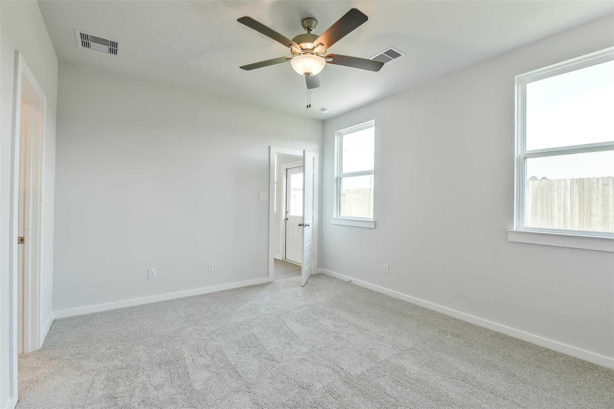 Bright secondary bedroom with ceiling fan, neutral walls, carpet floor, and window views in Davidson Homes The Colorado F, Cleveland, Texas
