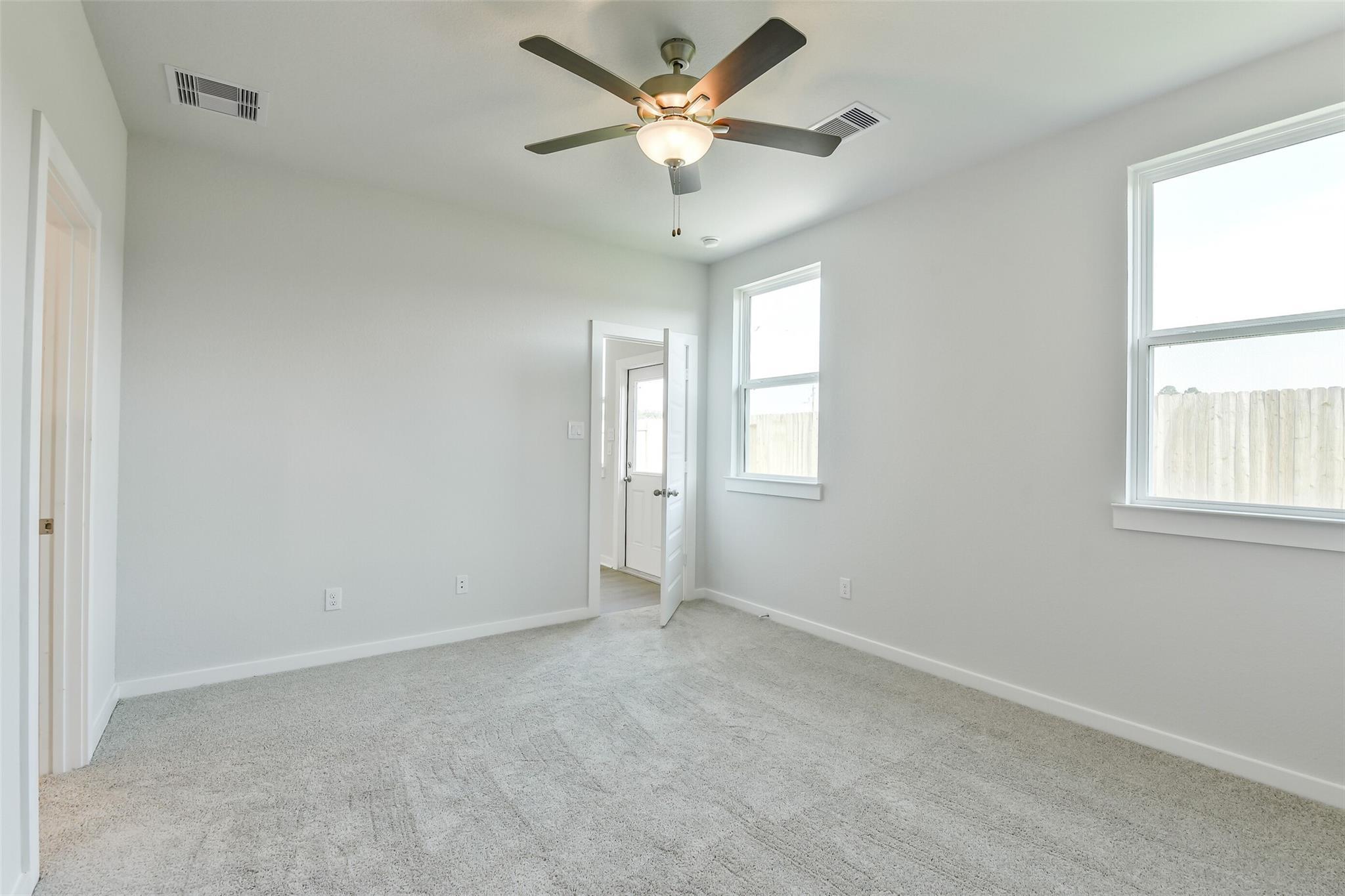 Bright secondary bedroom with ceiling fan, carpet floors, and backyard view in Davidson Homes The Colorado F, Cleveland, TX