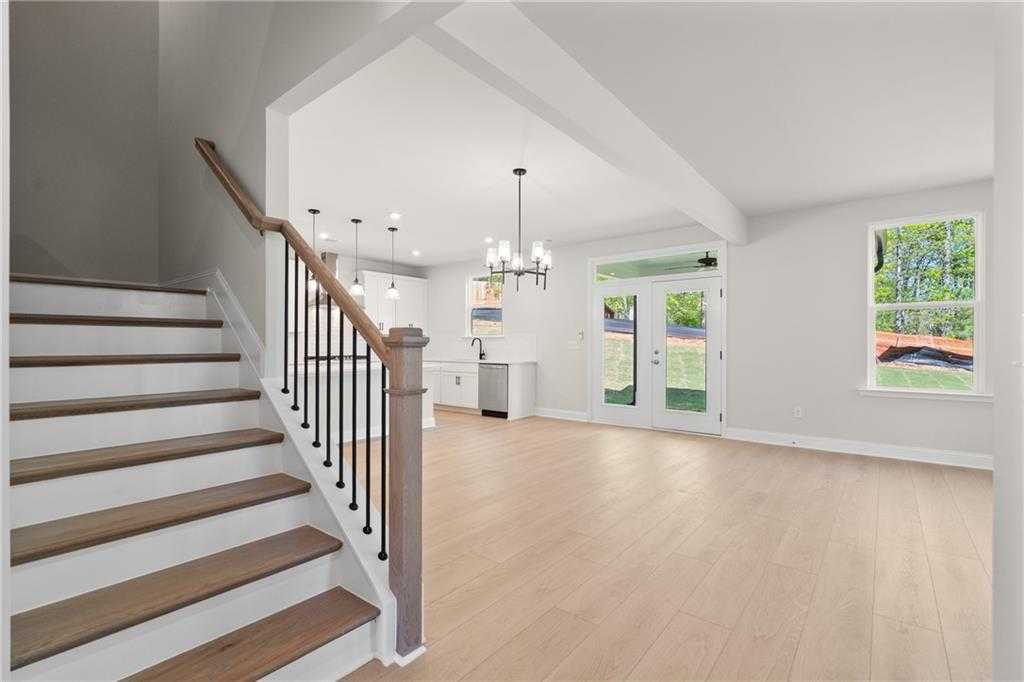 Open foyer featuring wooden staircase with black balusters and white kitchen archway in Davidson Homes The Hickory B, Buford, GA