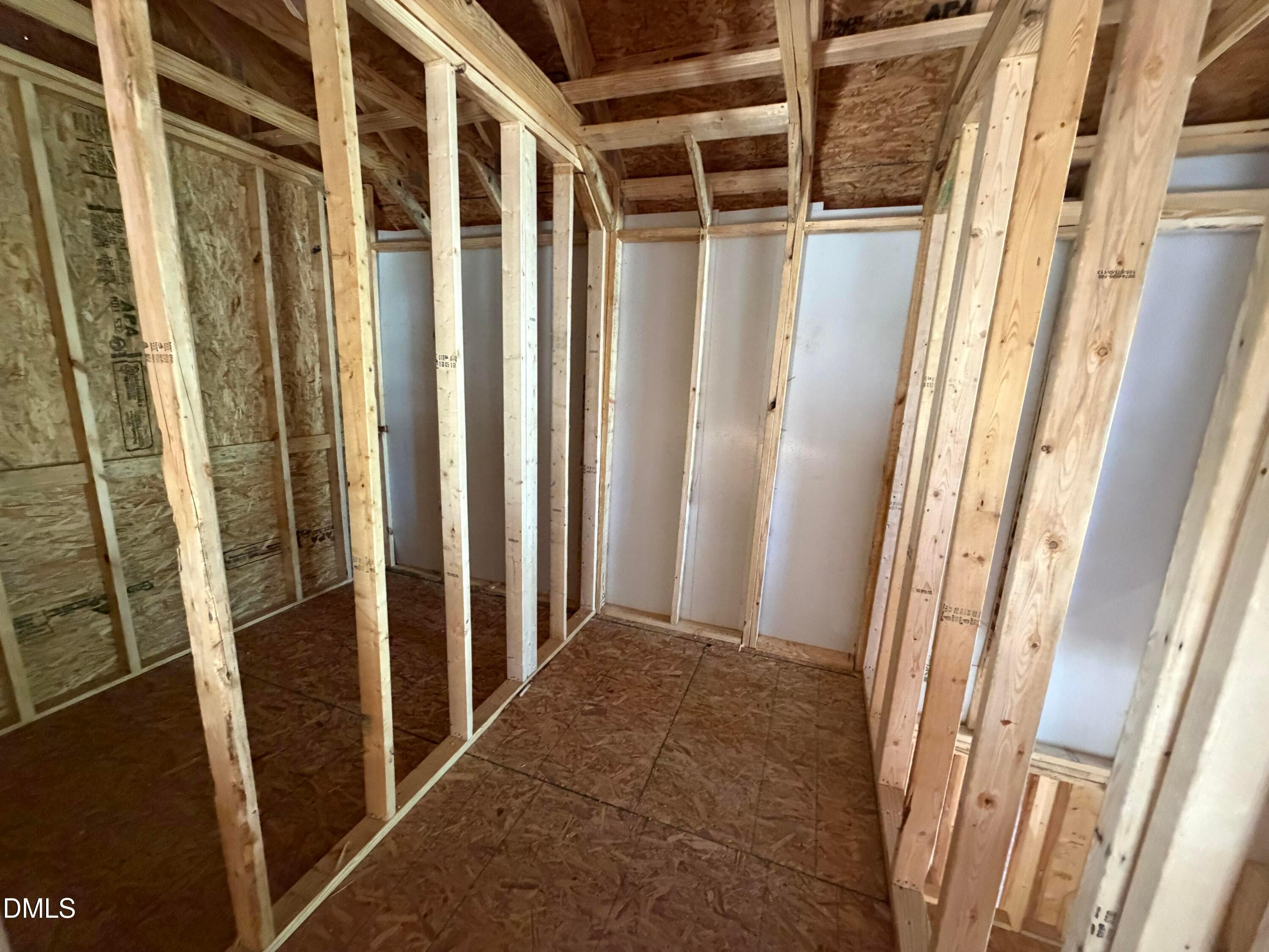 Framed interior room with wooden studs, plywood subfloor, and exposed trusses in Davidson Homes The Hickory II C, Lillington, NC