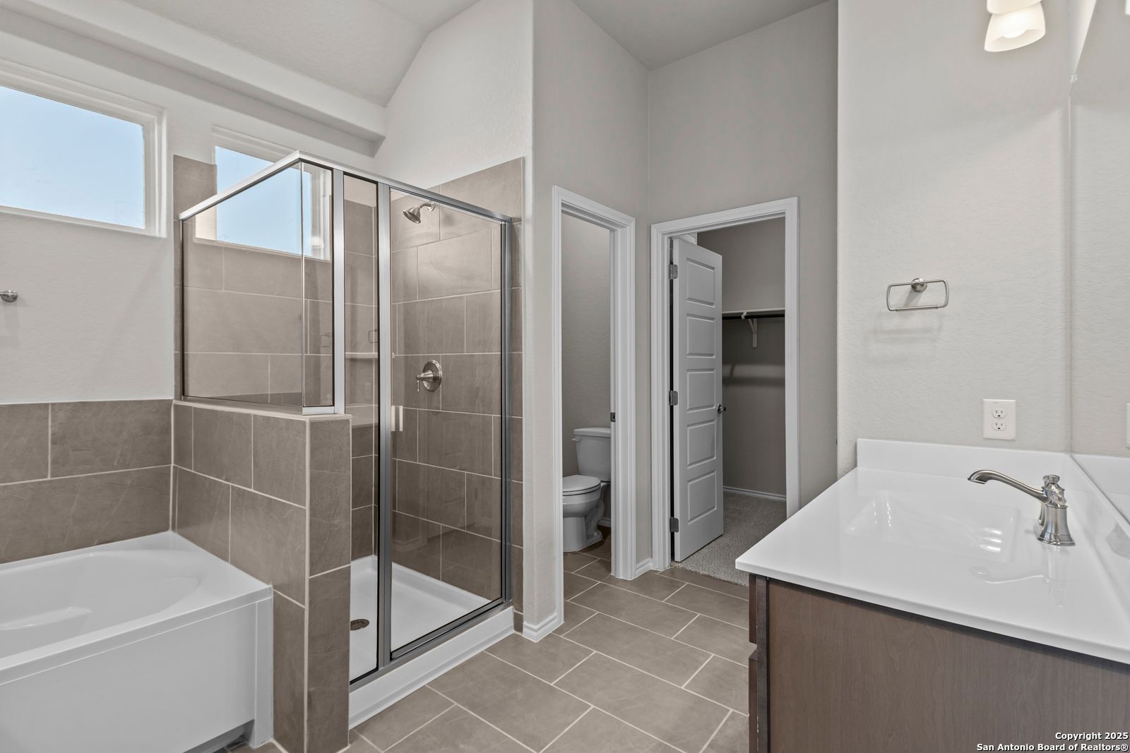 Modern master bathroom featuring glass walk-in shower, double sink vanity, and neutral tile in Davidson Homes The Collin B, Seguin, Texas