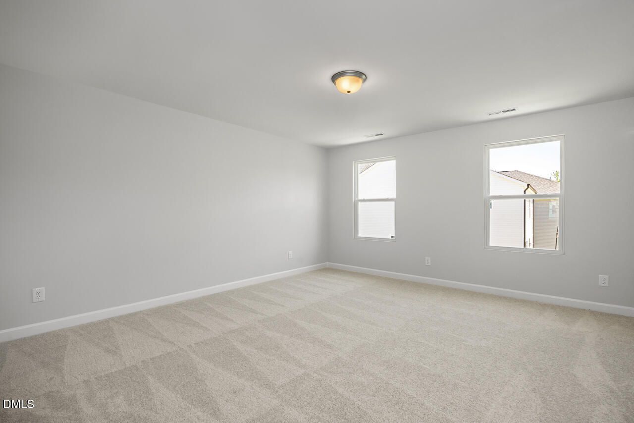 Spacious, carpeted bedroom with neutral walls in The Adalynn A floor plan at Gregory Village in Lillington, North Carolina.