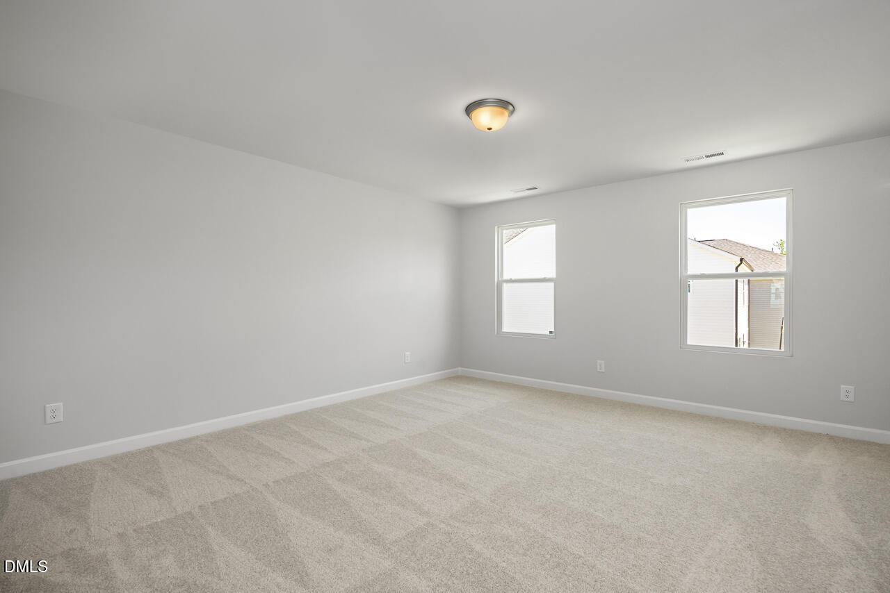 Spacious, carpeted bedroom with neutral walls in The Adalynn A floor plan at Gregory Village in Lillington, North Carolina.