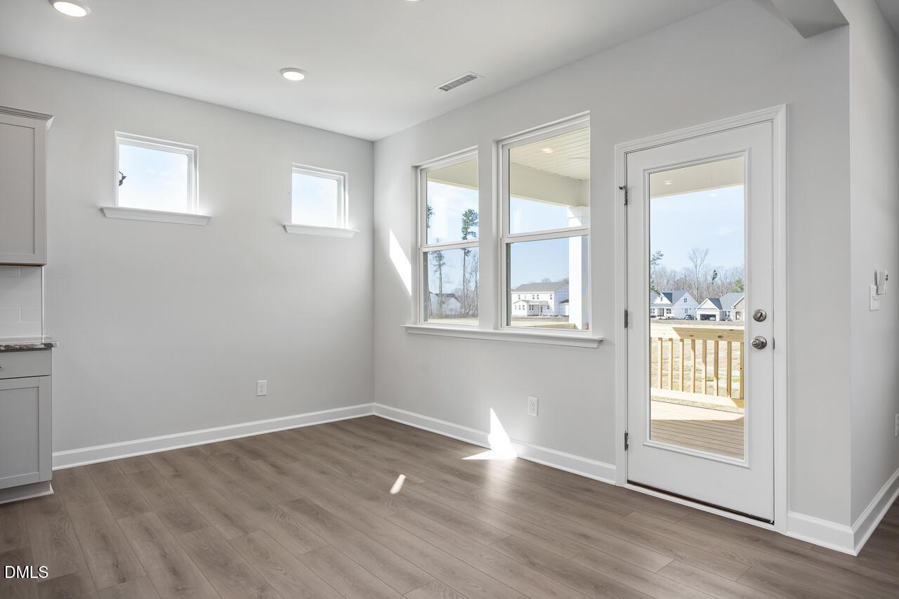 Bright sunlit room with gray walls, hardwood floors, large windows, and deck door in 5-bedroom Davidson Homes The Willow G, Angier, NC