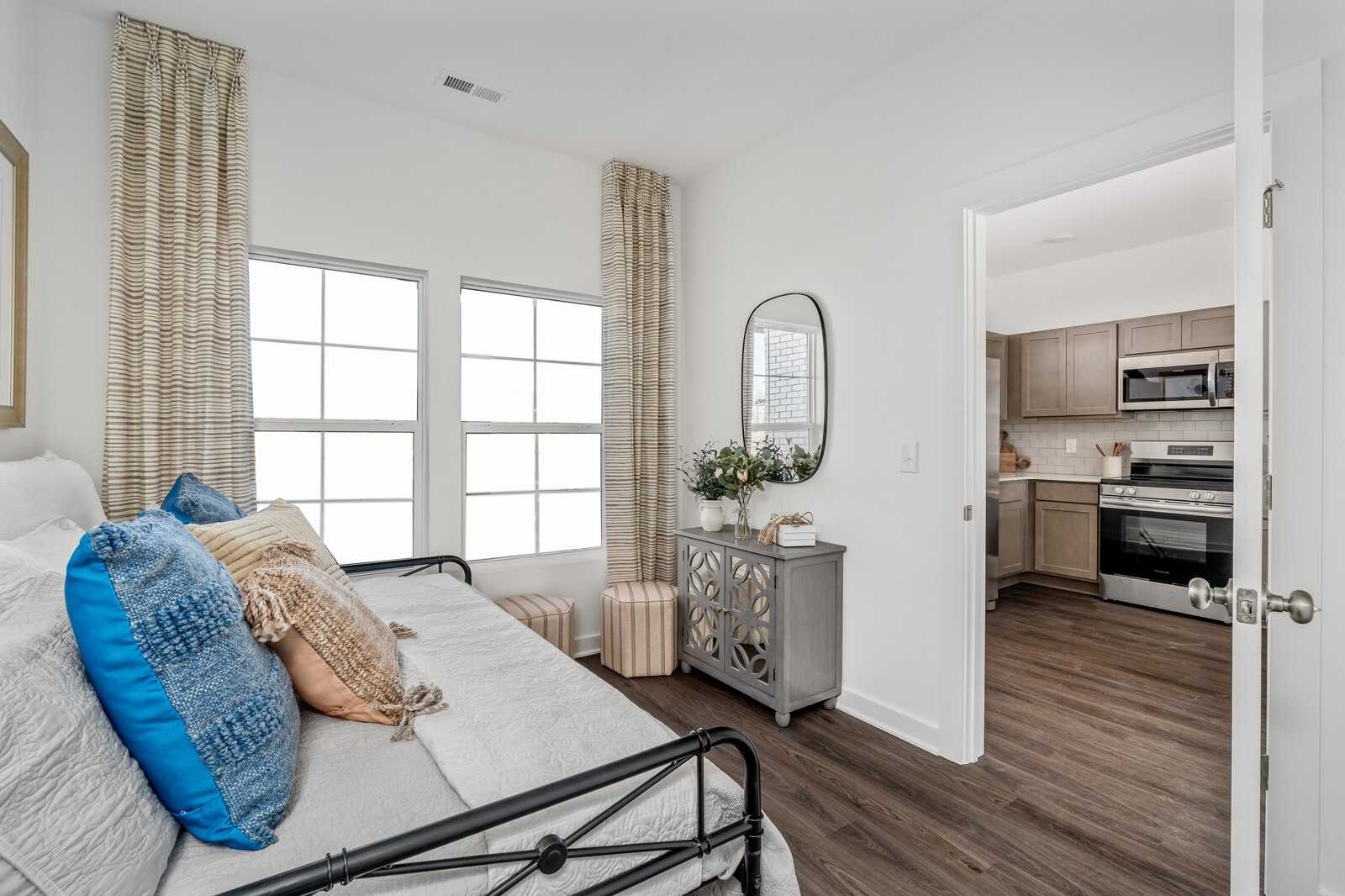 Cozy daybed with blue pillows in sunlit nook opening to modern kitchen with stainless appliances in Davidson Homes Cumberland A, Gallatin TN