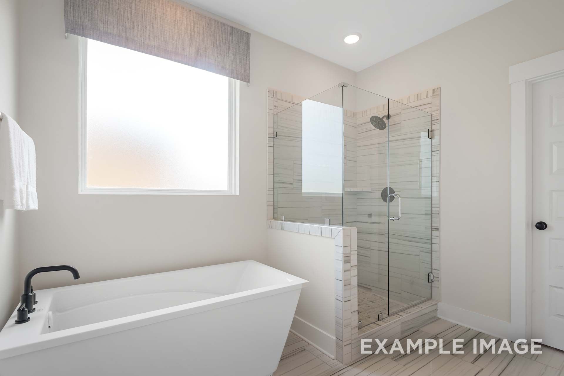 Elegant master bathroom with freestanding tub, glass shower, and frosted window in Davidson Homes Ridgeport C, Gallatin, TN