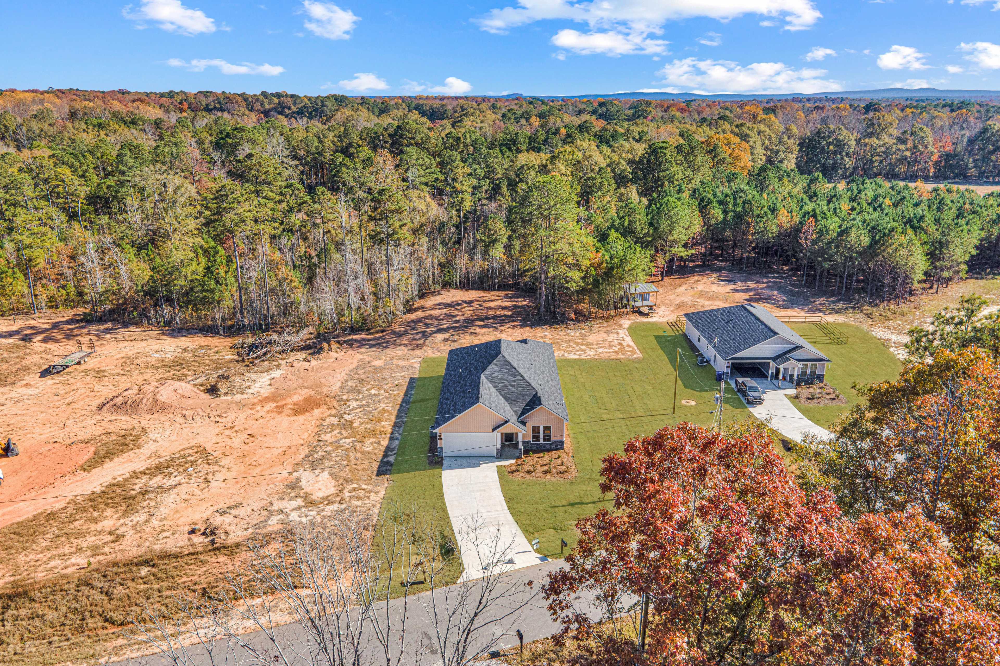 Aerial view of new single-story home with gray shingled roof at Silver Oak in Cusseta Alabama surrounded by wooded lots