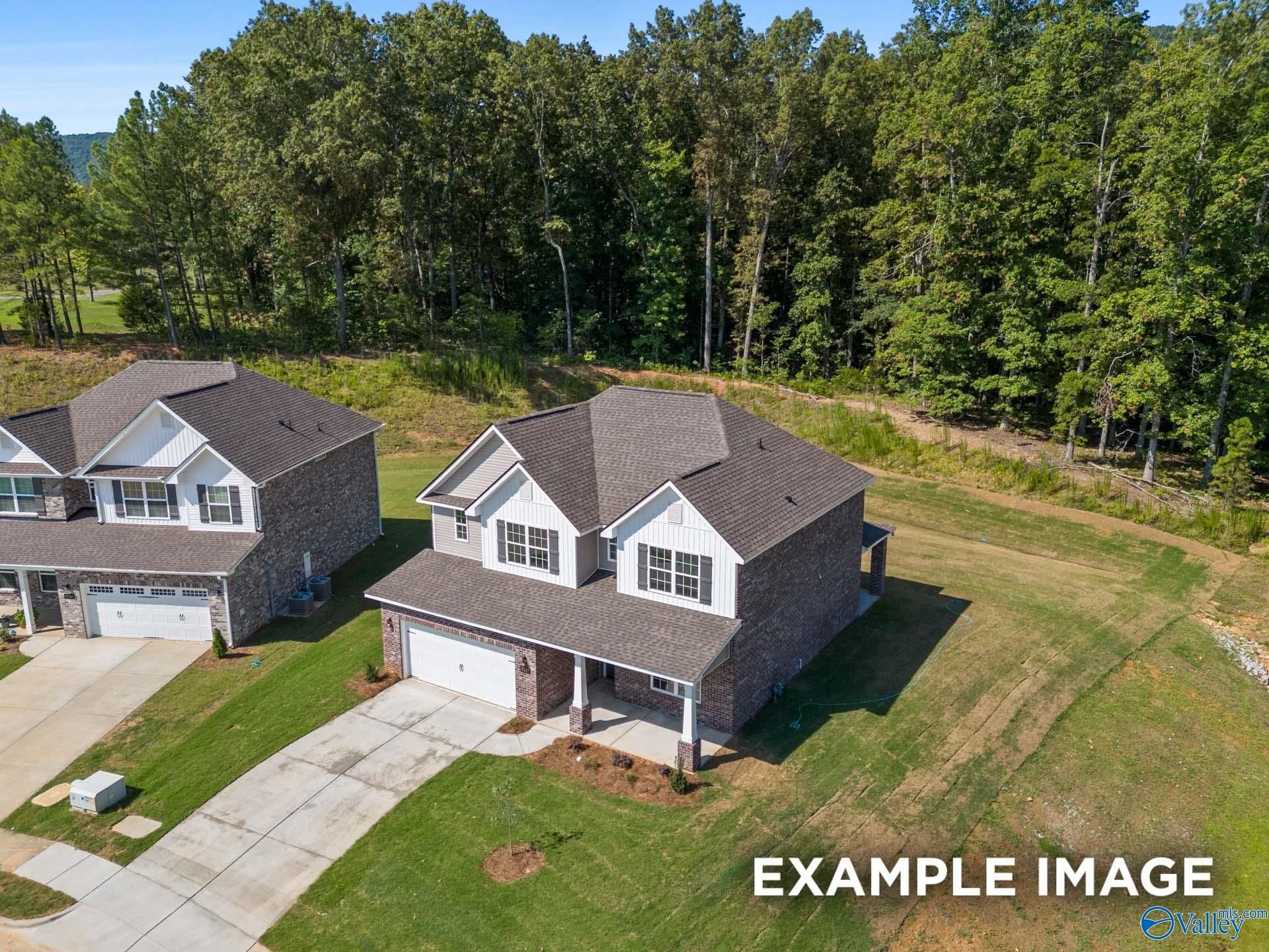 Aerial view of 2-story brick and siding home with 2-car garage and driveway amid wooded lot in The Highlands, Arab, Alabama Shelby C