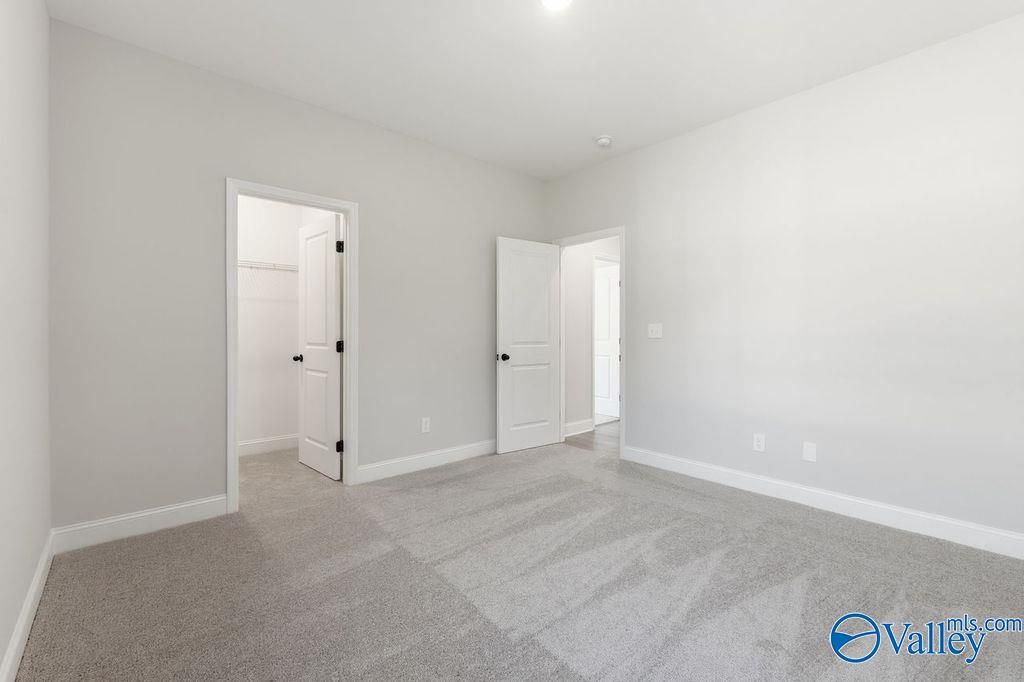 Spacious bedroom with gray carpet, light walls, and double doors in Davidson Homes The Montgomery B, Hartselle Alabama