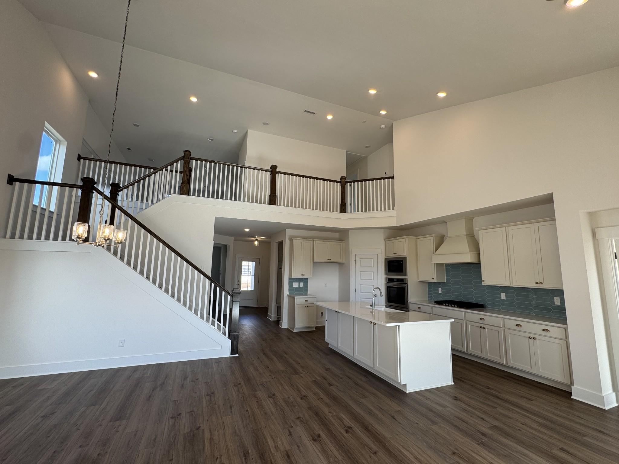 Open kitchen with white island, blue backsplash, and staircase to loft in Davidson Homes The Ridgeport, Gallatin, TN