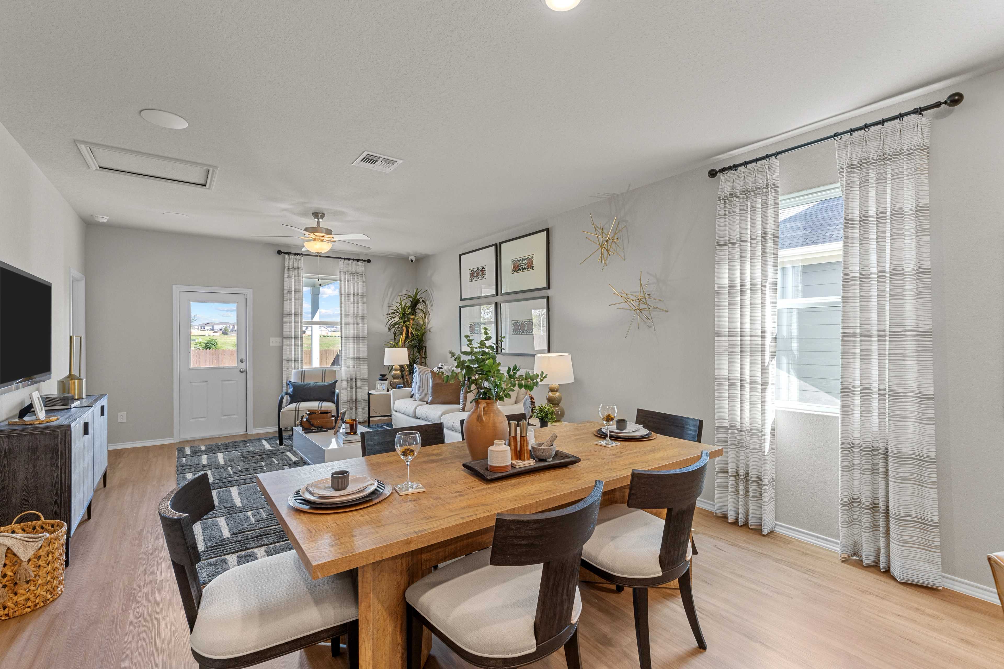 Spacious dining area in The Sabine C home design by Davidson Homes, San Antonio, featuring wooden table, upholstered chairs, and sheer curtains